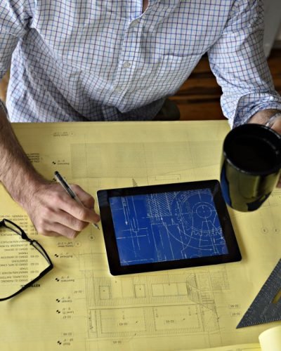 overhead-view-of-architect-working-on-design-blue-prints-at-drafting-table-using-various-tools-and_t20_x6aay2 (1)